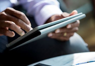 A close up of a person's hands holding and working on a tablet.
